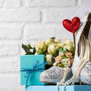 Beautiful bridal high heels composed with bouquet and other bridal decor on blue box.